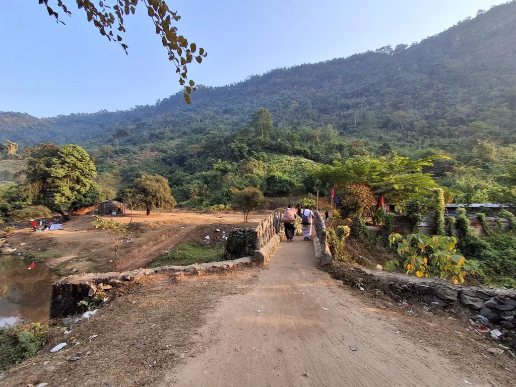 Local women crossing the iconic bridge at Kopili Picnic Spot, showcasing traditional rural life Local women crossing the iconic bridge at Kopili Picnic Spot, showcasing traditional rural life.