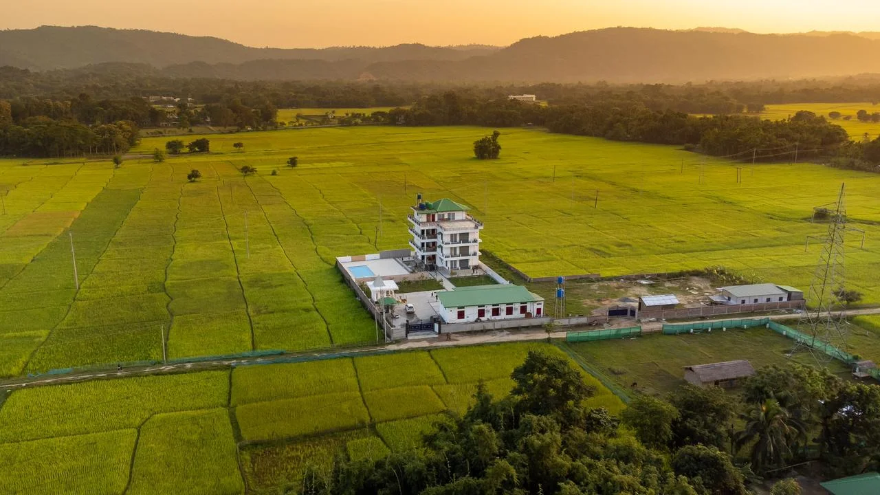 Aerial view of The Kaziranga Address surrounded by paddy fields and hills