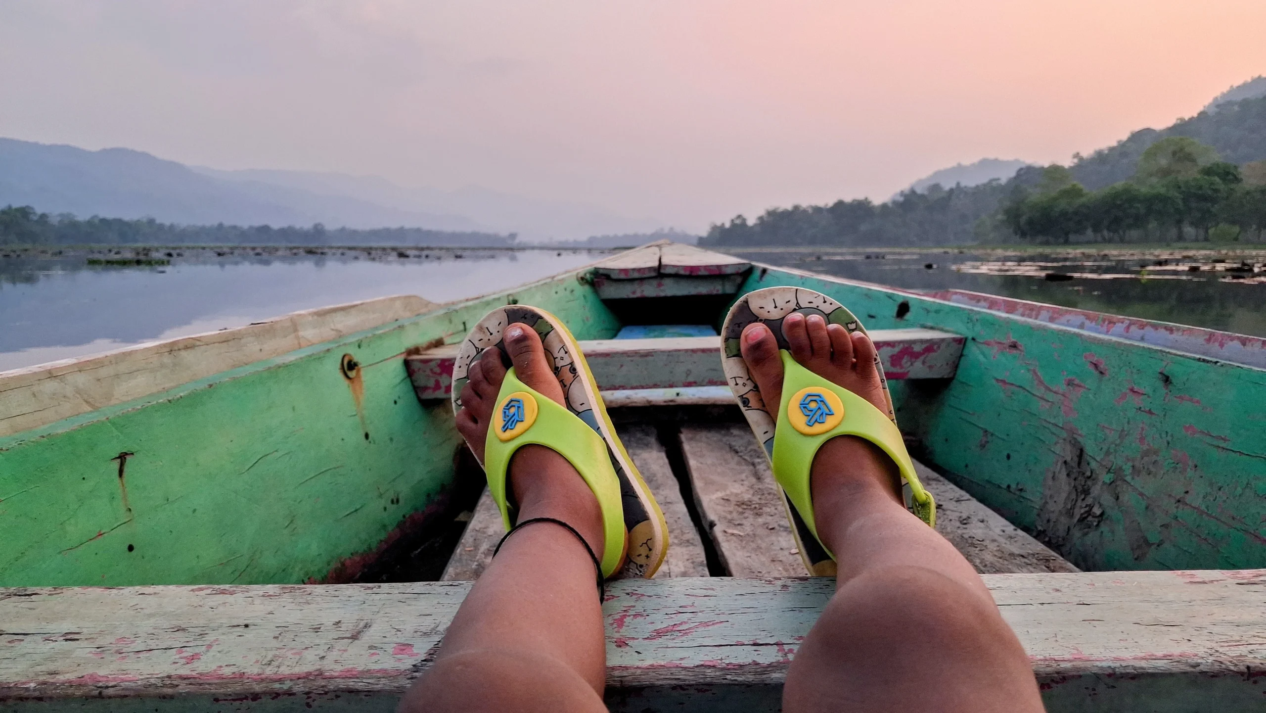 View of Chandubi Lake from a boat with a child’s feet and boat bow in the foreground